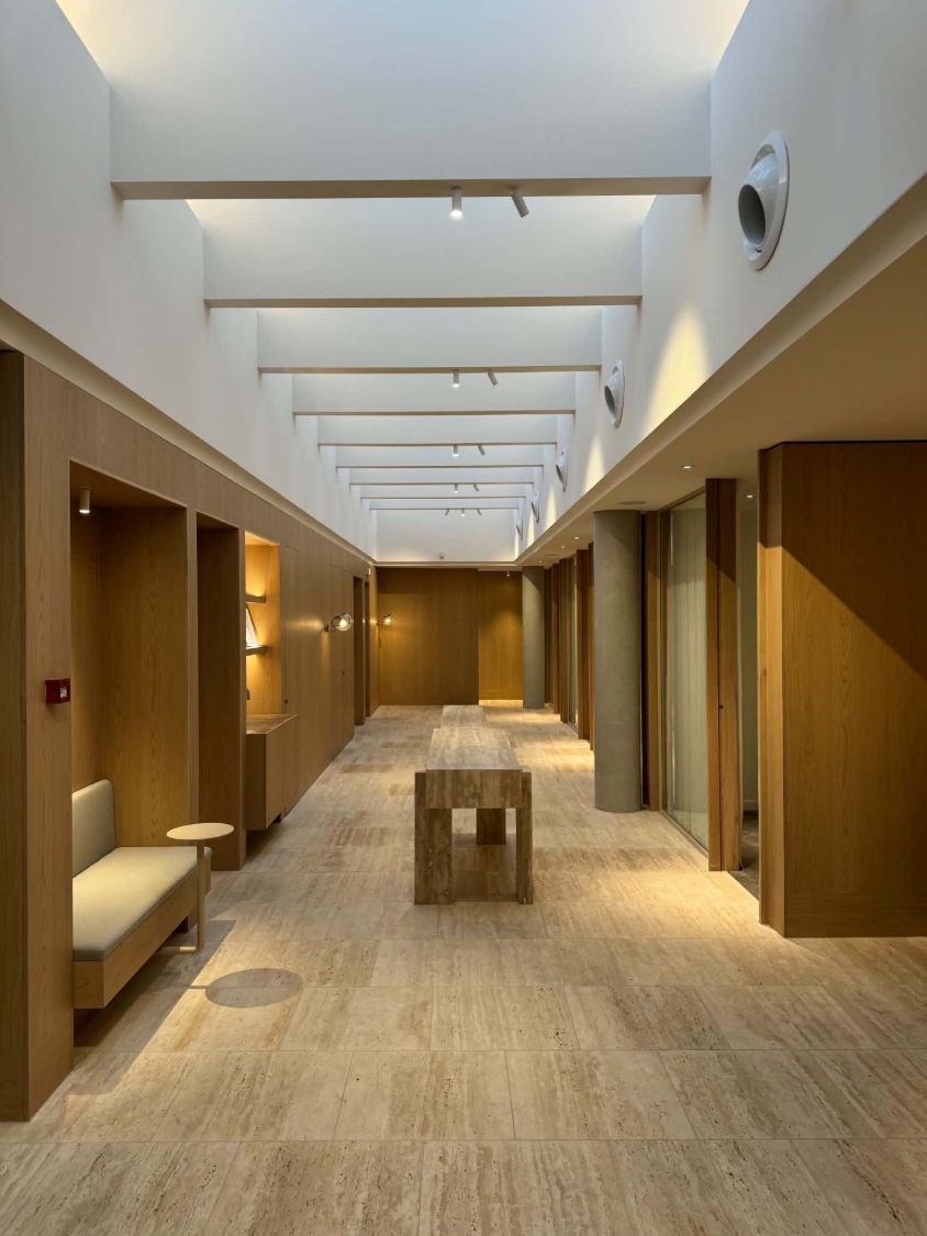 Long commercial corridor with track spotlights along the skylight beams and concealed wall lighting