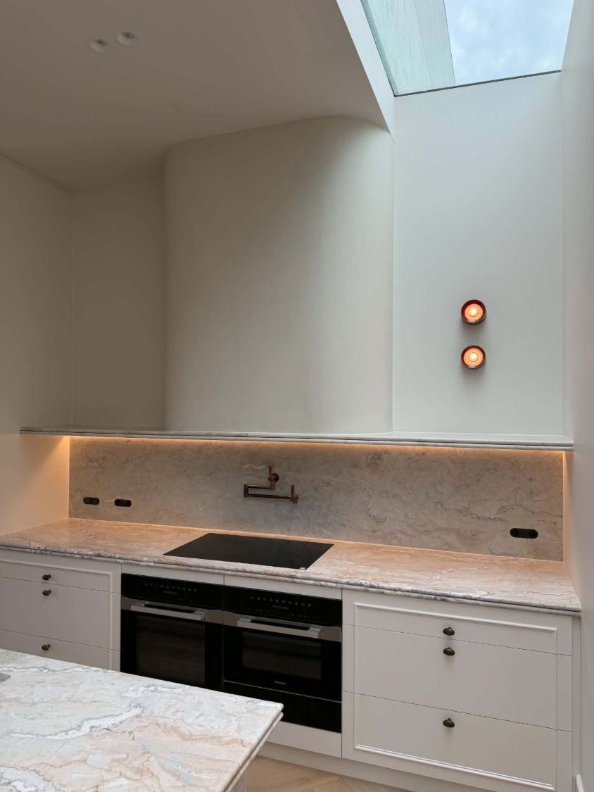 Kitchen with LED strip lighting under a stone shelf above the splashback, and two round wall lights