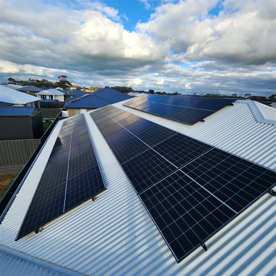Rows of black solar panels across a light grey corrugated iron roof